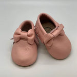 Close-up of soft pink leather baby moccasins with bow detail